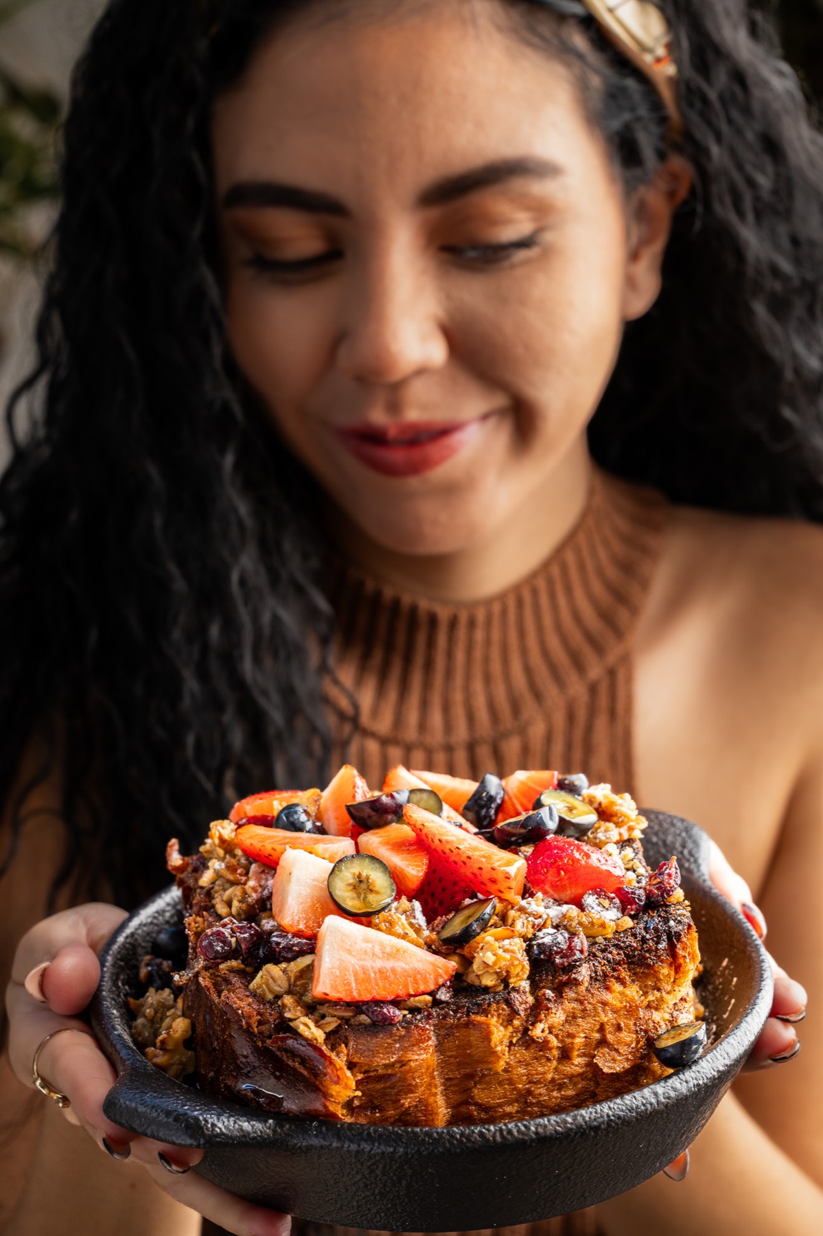 Mujer sosteniendo un pan francés con frutos rojos
