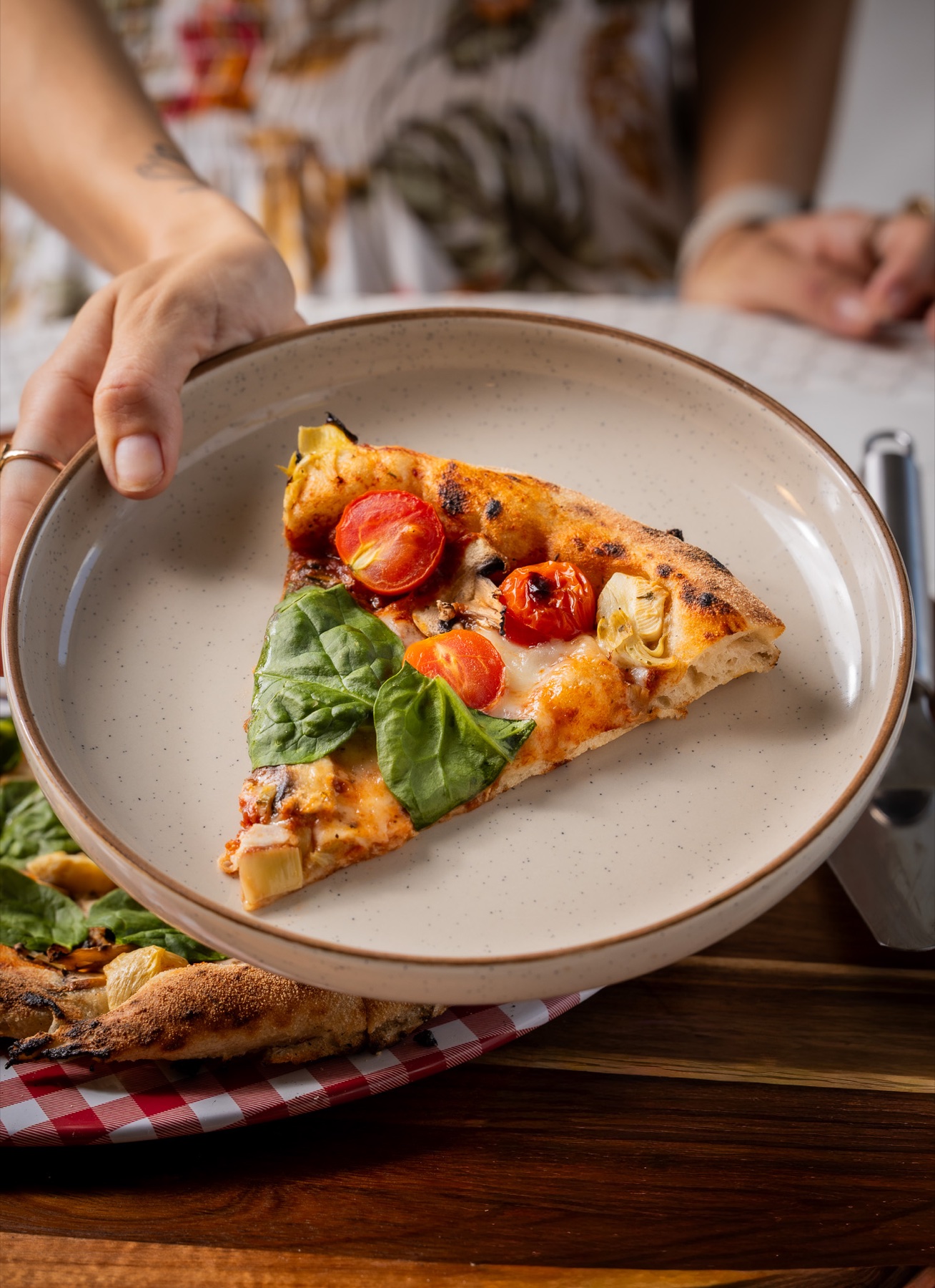 Rebanada de pizza artesanal con tomates, espinaca y alcachofa