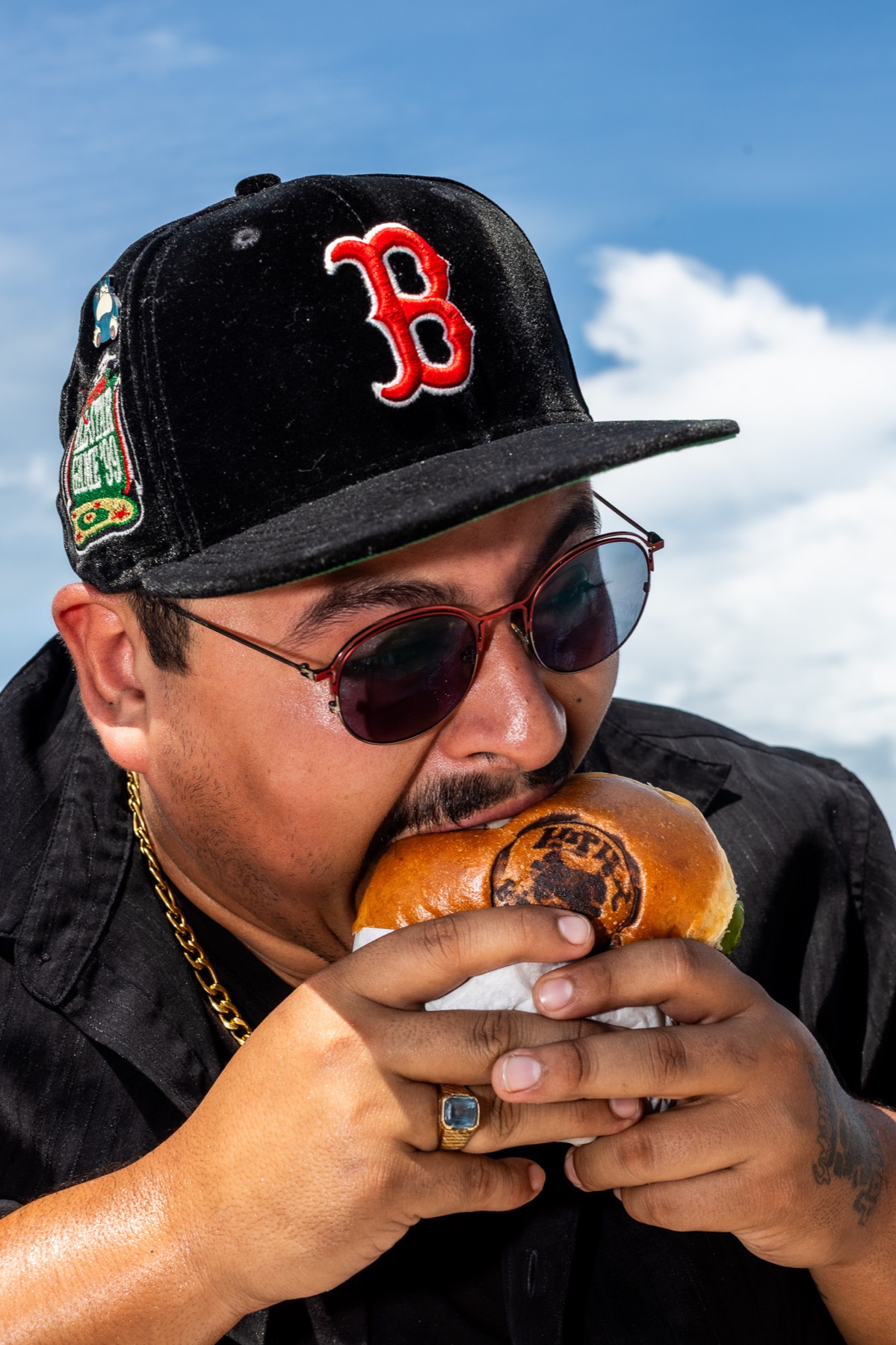 Comensal disfrutando una hamburguesa bajo el cielo azul