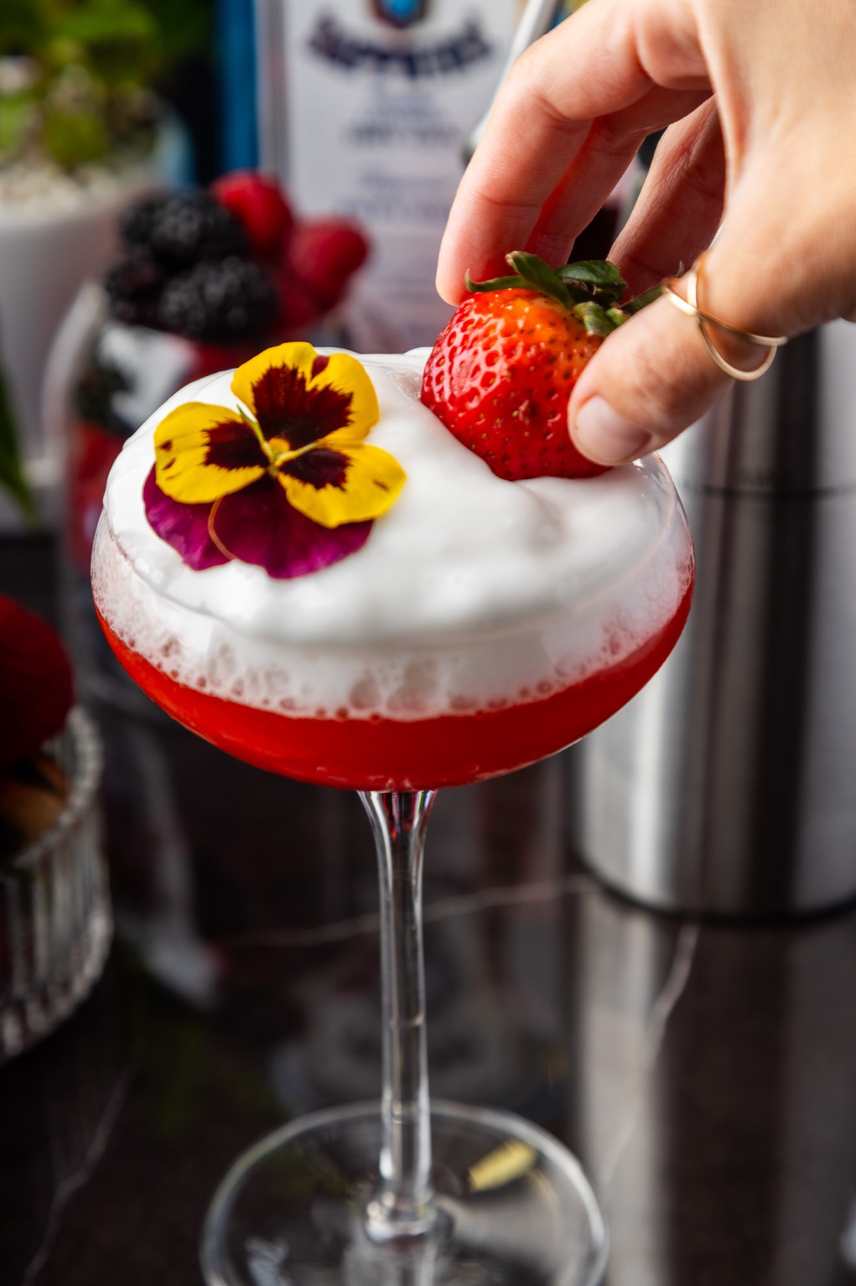 Coctel rojo con espuma, fresa y flor comestible