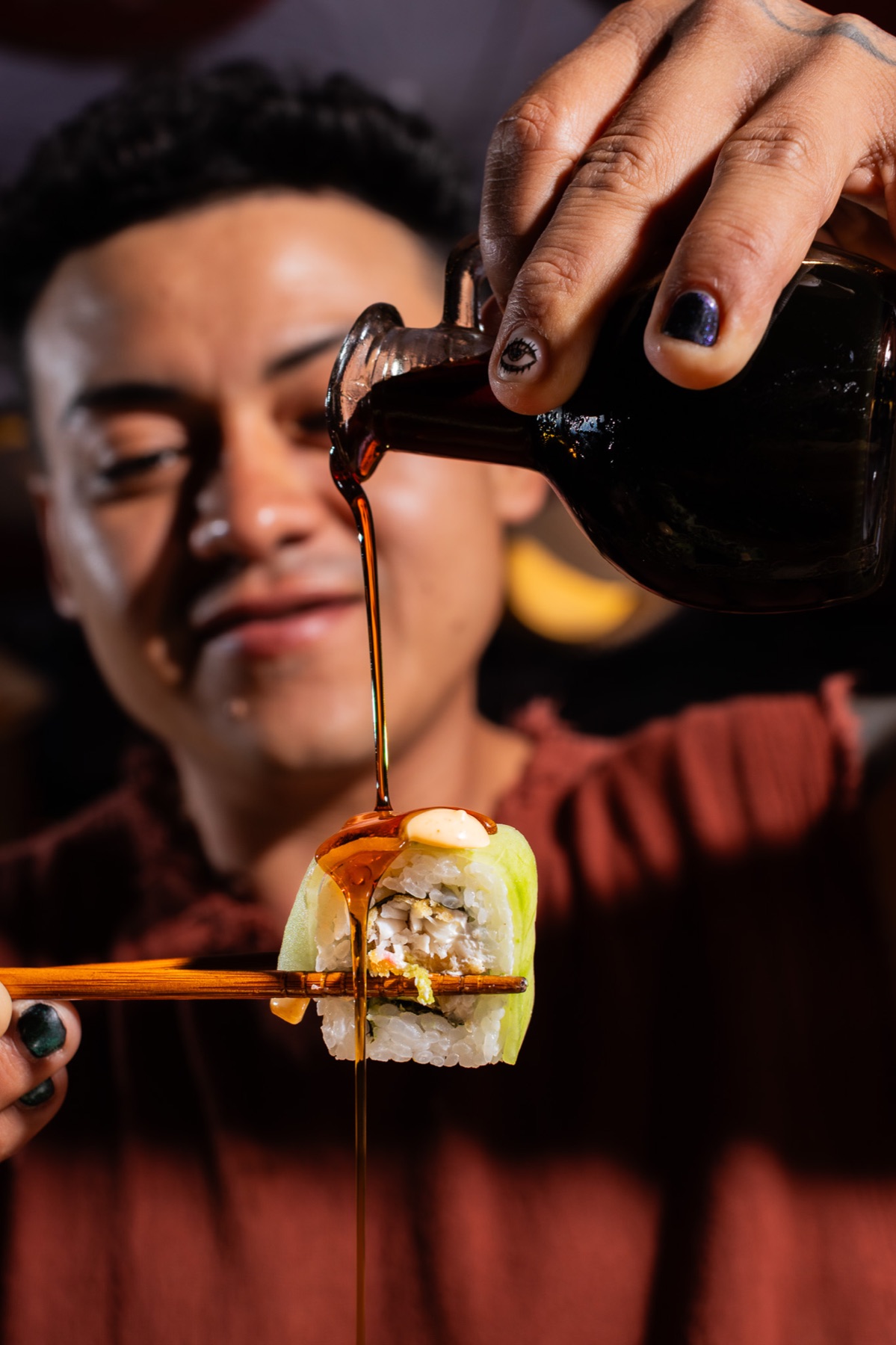 Comensal sirviendo salsa sobre una pieza de sushi