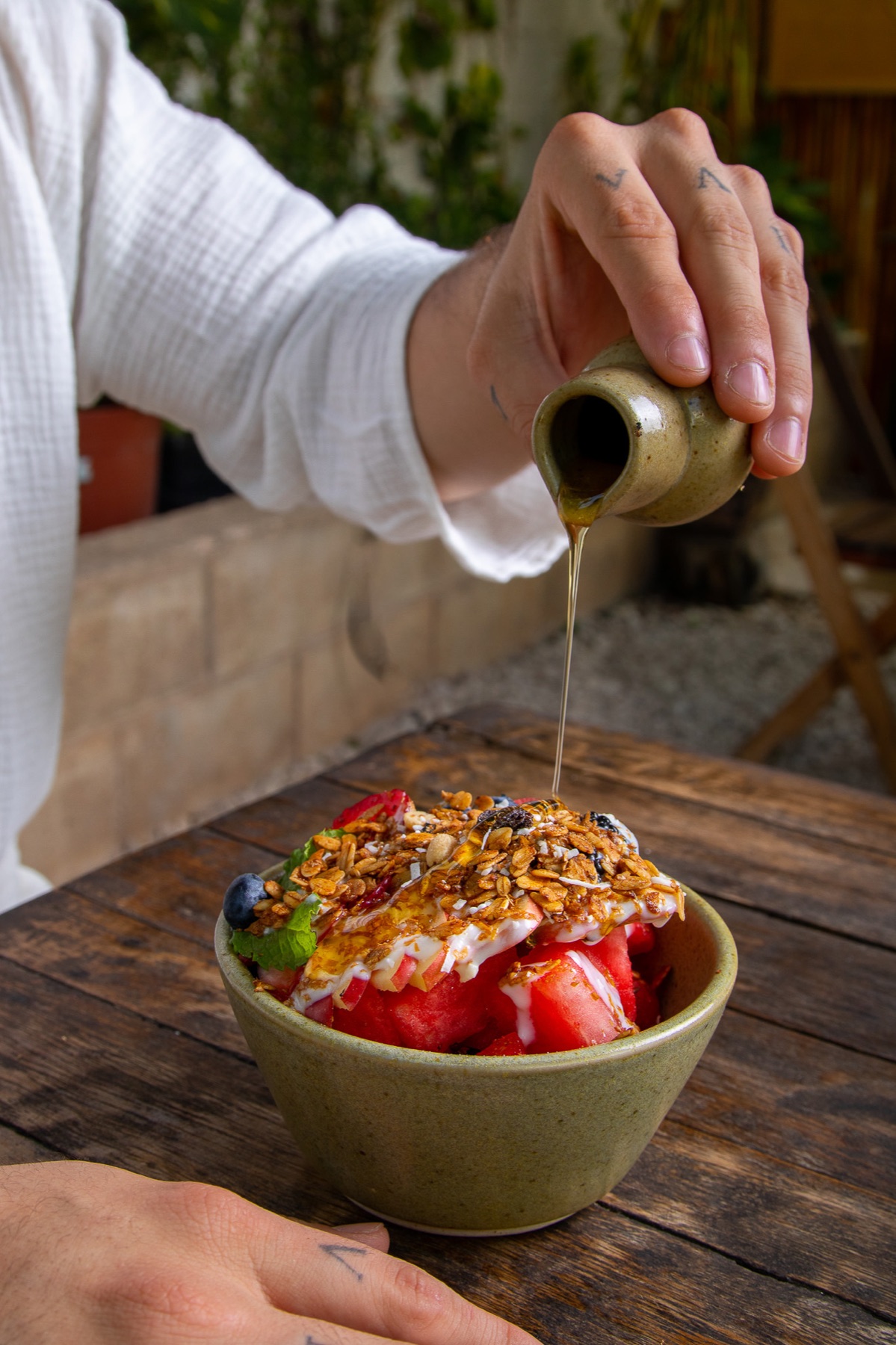 Miel cayendo sobre un bowl de fruta y granola