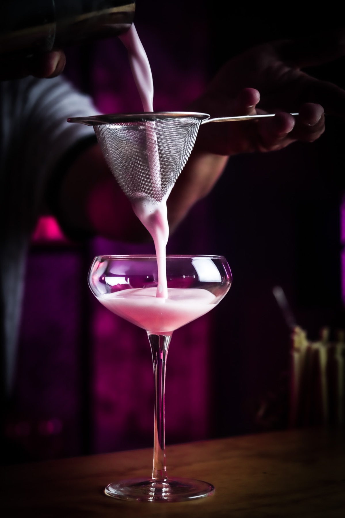Coctel rosa colándose en una copa